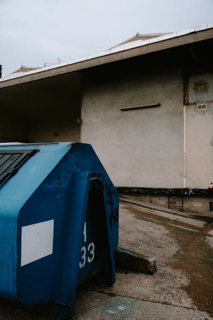 The image features the rear section of a white commercial van parked on a street with three large blue rubbish bags positioned on the pavement next to it. The bags are made of plastic, with slightly c